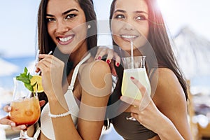 Beautiful women on beach enjoying cocktails