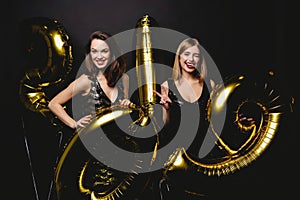 Beautiful Women Celebrating New Year. Happy Gorgeous Girls In Stylish Party Dresses Holding Gold 2019 Balloons