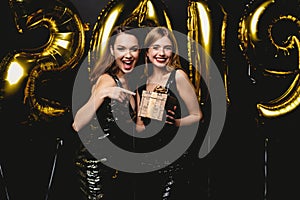 Beautiful Women Celebrating New Year. Happy Gorgeous Girls In Stylish Party Dresses Holding Gold 2019 Balloons