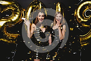 Beautiful Women Celebrating New Year. Happy Gorgeous Girls In Stylish Party Dresses Holding Gold 2019 Balloons