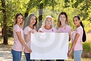 Beautiful women of different ages with pink ribbons holding poster outdoors. Breast cancer concept