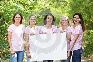 Beautiful women of different ages with pink ribbons holding poster outdoors. Breast cancer concept