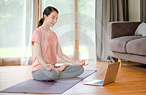 Beautiful women doing yoga with different posture and look example from laptop also she look happy and relax. Concept of workout