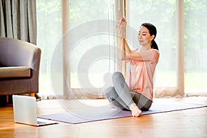 Beautiful women doing yoga with different posture and look example from laptop also she look happy and relax. Concept of workout