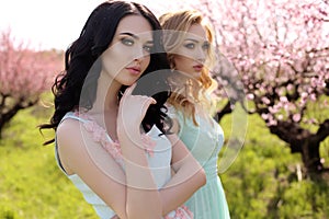 Beautiful women in elegant dresses posing in blossom garden