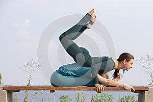 Beautiful women exercizing yoga together on the nature. Concept of relationship, love, summer, weekend, honeymoon, healthy