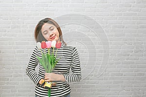 Beautiful women with flowers tulips in hands on a light background