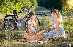 Beautiful young woman having picnic with girl at river