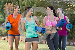 Beautiful women holding exercise-mat in park