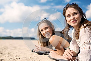 Beautiful women lying on beach laughing looking away