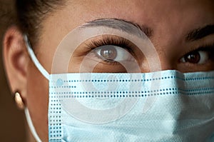 Beautiful Women In A Medical Mask. Close-up of a young girl with a surgical mask on her face against SARS-cov-2