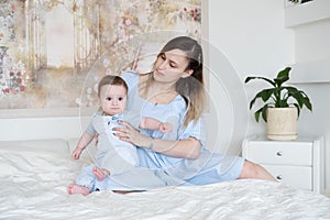beautiful women mother holding her baby boy son sitting on bed at home
