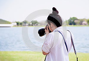 Beautiful women professional photographer takes images with DSLR camera., In the park.