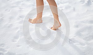 Beautiful women's feet walk barefoot on freshly fallen snow