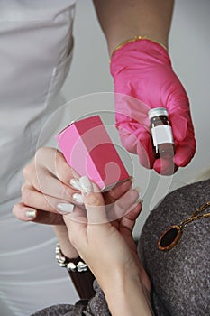 Beautiful women`s manicured hands and doctor`s hands in pink gloves are holding medications