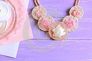 Beautiful women`s necklace. Women`s necklace made of ribbons, cords and felt. Materials to create jewelry on a wooden table