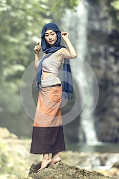 Beautiful women in traditional dress dancing at waterfall