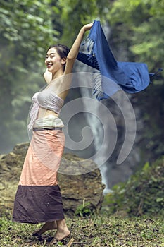 Beautiful women in traditional dress dancing at waterfall