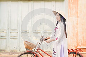 Beautiful women Vietnam with white Ao Dai dress and red bicycle