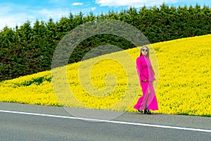 Beautiful women walking in amazing field of yellow rapeseed in the countryside. Canola oil plants