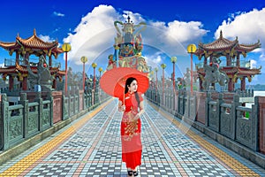 Beautiful women wearing dresses red cheongsam holding an umbrella walking on the bridge at Zuoying Yuandi temple,Taiwan