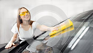 Beautiful women worker washing windshield with sponge car service