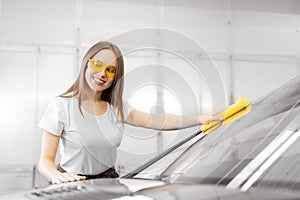 Beautiful women worker washing windshield with sponge car service