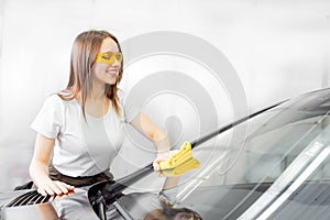 Beautiful women worker washing windshield with sponge on car, window clean spray