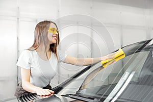 Beautiful women worker washing windshield with sponge on car, window clean spray