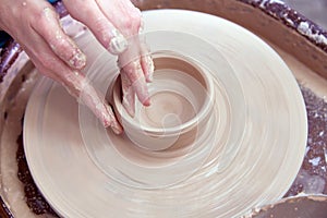 Beautiful women& x27;s hands make ceramic dishes on a spinning potter& x27;s wheel. soft focus.