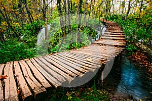 Beautiful wooden bridge pathway in the deep forest over a turquoise colored water creek in Plitvice, Croatia, UNESCO