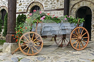 A beautiful wooden cart full of flowers. Yard decor for a house.
