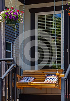 Beautiful wooden front porch swing with comfortable pillows. Outdoor wooden porch swing bench with color pillows