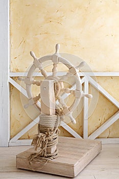 Beautiful wooden ship wheel with wire rope in light room with yellow walls