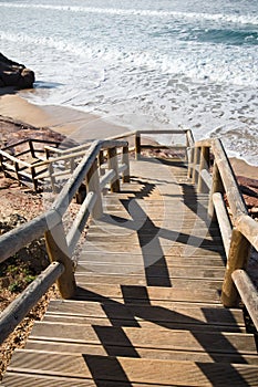 Beautiful wooden stairs going down to atlantic ocean on sandy beach