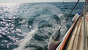 Beautiful wooden yacht breaks the waves, slow motion shot. Clear blue water. Splashes from the waves explode in