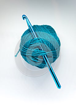 A beautiful wool yarn with a crochet needle on a white background.