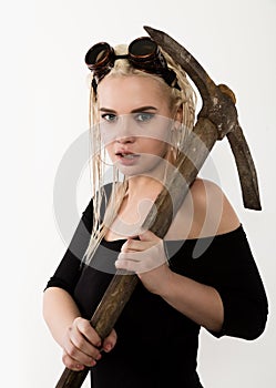 Beautiful worker with a pickaxe. Seductive and beautiful woman miner on a light background