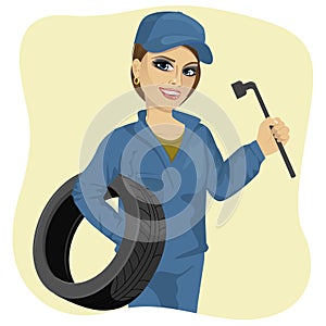 Beautiful working woman in car repair service holding tyre and wheel wrench