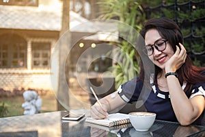 Beautiful working woman write on notebook about business