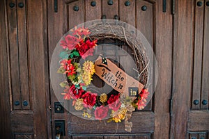 Beautiful wreath of dry twigs with flowers on a wooden door with the inscription Witches inside