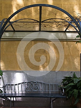 Beautiful Wrought Iron Outdoor Bench against Mediterranean Bisque color wall with pergola