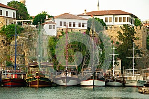 Beautiful yachts and touristic boats in the marina, port of Antalya old town Kaleici, Turkey. Old historical stone castle wall on