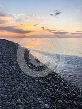Beautiful yellow bright sunset on the sea, river, lake, pond, water on the rocky beach of a tropical warm resort with round stones