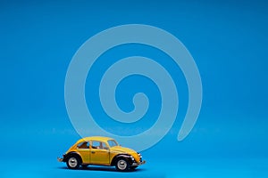 Beautiful yellow car figurine isolated on blue background