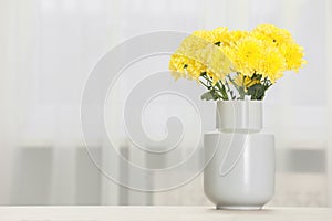Beautiful yellow flowers in vase on table at home, space for text