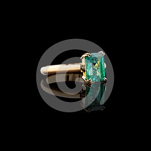 Beautiful yellow gold ring with diamonds and emerald on a black background