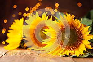 Beautiful yellow Sunflowers on wooden table at festive bokeh background.