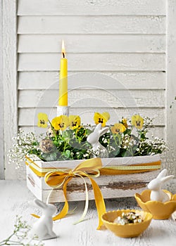 Beautiful yellow viola flowers with burning candle in the old vintage wooden box.