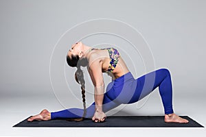 Beautiful yoga woman practice yoga poses on grey background.